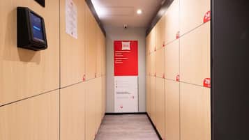 A hotel corridor with lockers, a digital keycard reader, and a sign with rental information.