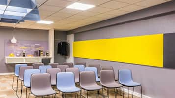 Un salón de conferencias con una fila de sillas, una pared de acento amarilla y una lámpara colgante.