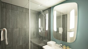 Un baño moderno con cabina de ducha de vidrio, un lavabo blanco y un espejo grande.