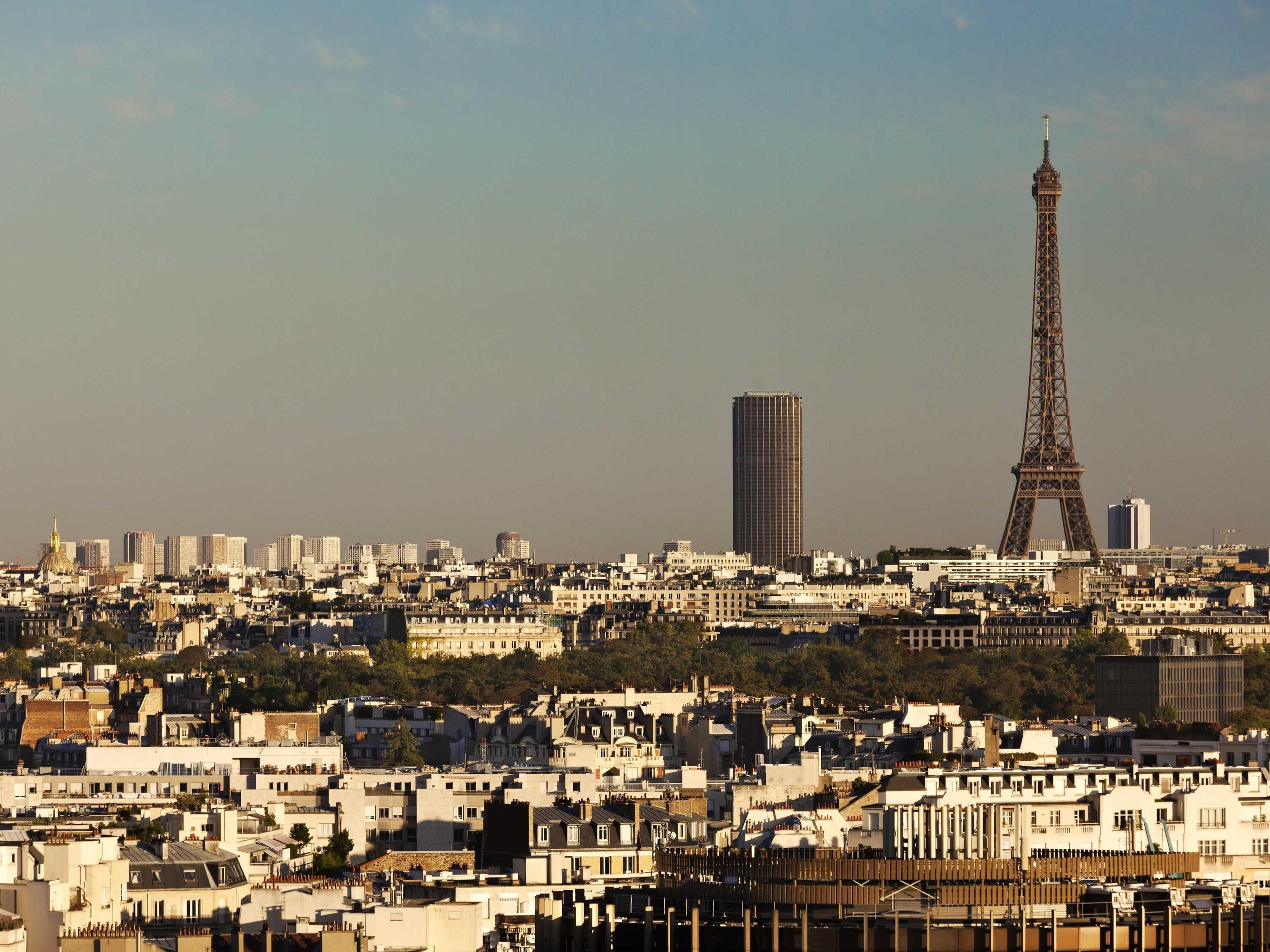 Un horizonte urbano con la Torre Eiffel y un rascacielos moderno.