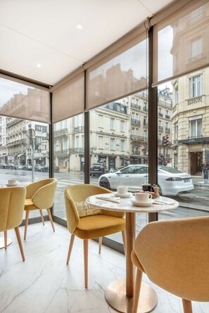 A cafe with large windows, yellow chairs, and a marble floor. - Hôtel Claridge (Paris)