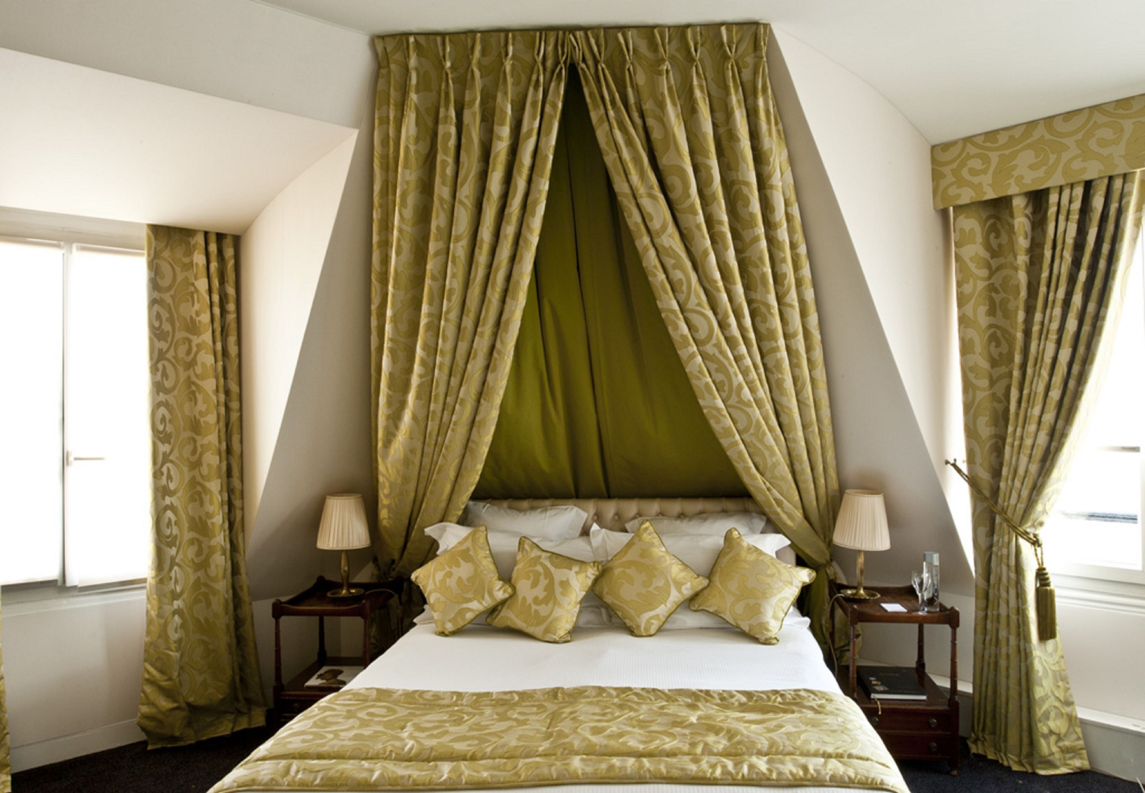 Een slaapkamer met een hemelbed, twee nachtkastjes en gordijnen.