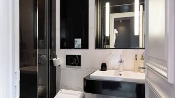 Une salle de bain moderne avec une douche à parois de verre, des toilettes blanches, un meuble-lavabo noir et blanc et un grand miroir.