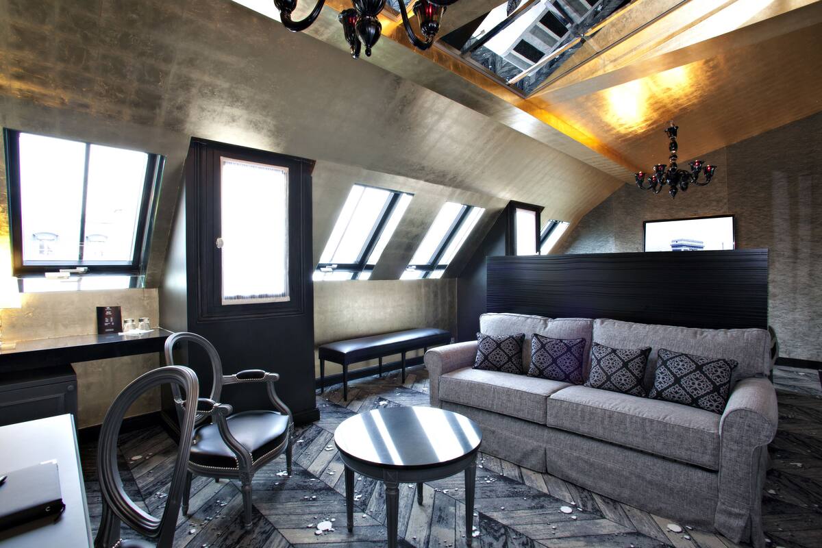 Ein stilvolles Loft mit hohen Decken, Dachfenstern, einer Couch, einem runden Tisch und einer Bar.