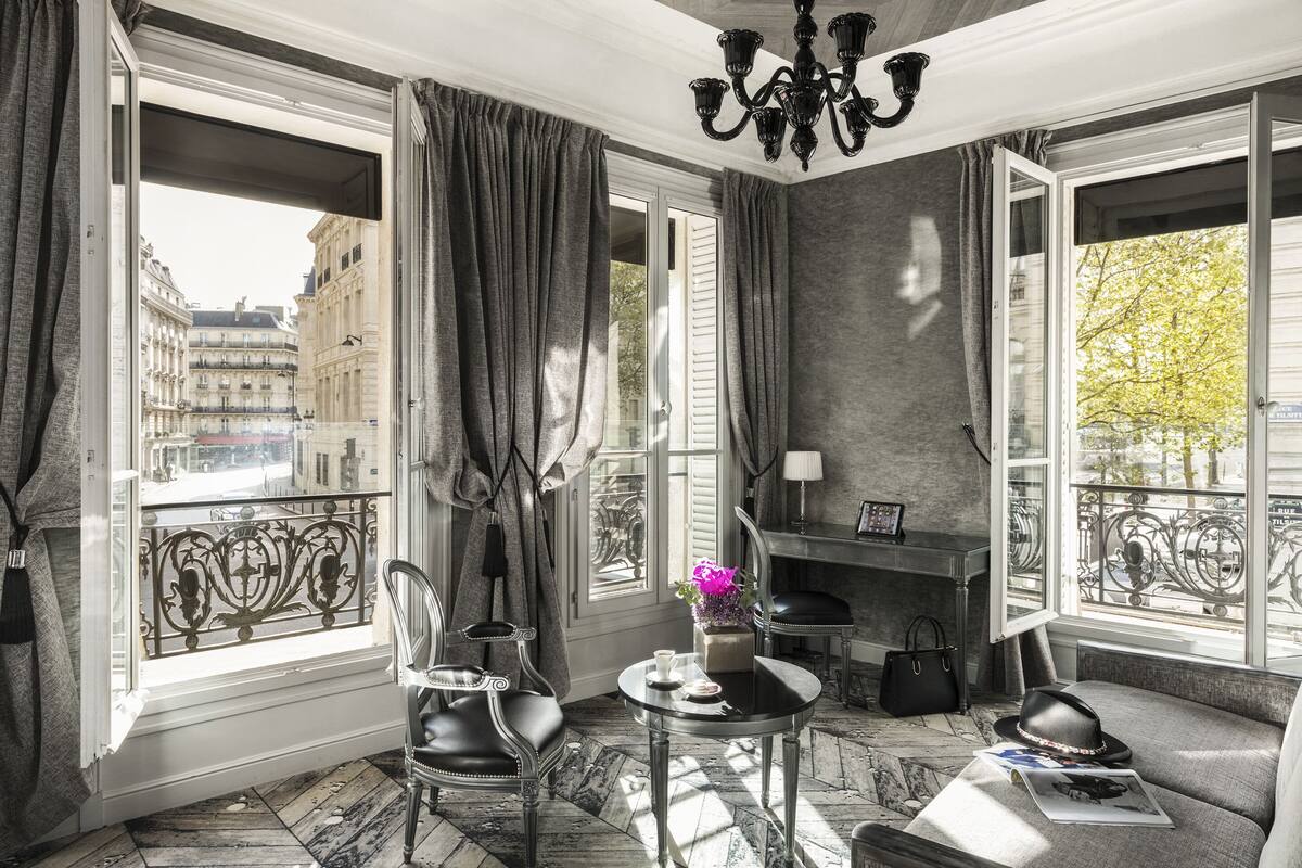 Ein Zimmer mit Blick auf Paris, ausgestattet mit einem Tisch, einer Vase, einem Sessel und einem Sofa.