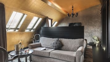 Um quarto moderno estilo loft com teto alto, claraboias, um sofá, uma pequena mesa com bebidas e um lustre decorativo.