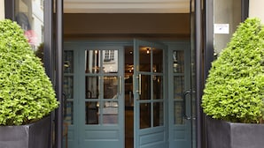 A hotel entrance with a blue door, a doormat, and a sign indicating a Michelin award. - Hotel Therese (Paris)