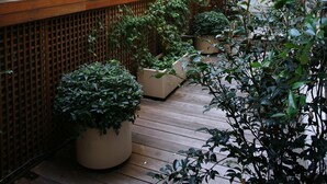 A wooden deck with potted plants and a wooden fence. - Hotel Therese (Paris)