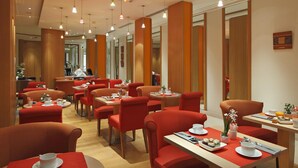 A modern dining area with red upholstered chairs and tables, featuring a clean and contemporary design. - Hôtel Westside Arc de Triomphe (Paris)