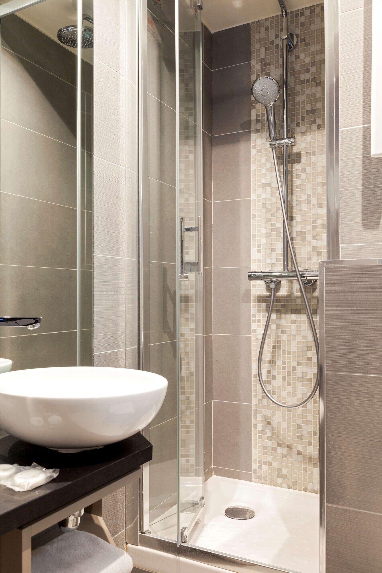 Un ba ño moderno con ducha de vidrio, lavamanos blanco y paredes de azulejos.