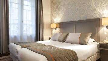 A hotel room with a large bed, two bedside tables, a nightstand, and a window with curtains.