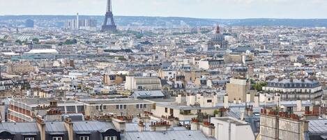 Un paisaje urbano con la Torre Eiffel al fondo, mostrando edificios urbanos densos y una variedad de estilos arquitectónicos.