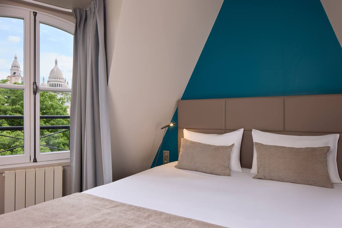 Une chambre avec un grand lit, une vue sur un bâtiment doté de coupoles et une fenêtre avec des rideaux.