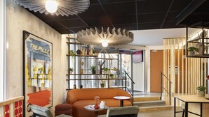 A modern interior with a sofa, chairs, a table, and a decorative ceiling light. - ibis Paris Nation Davout (Paris)