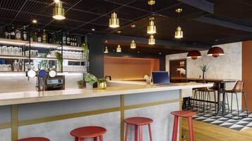 A modern bar area with a counter, stools, and pendant lighting.
