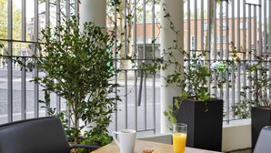 A table with a white mug, a glass of orange juice, and two cookies on a wooden table. - ibis Paris Nation Davout (Paris)