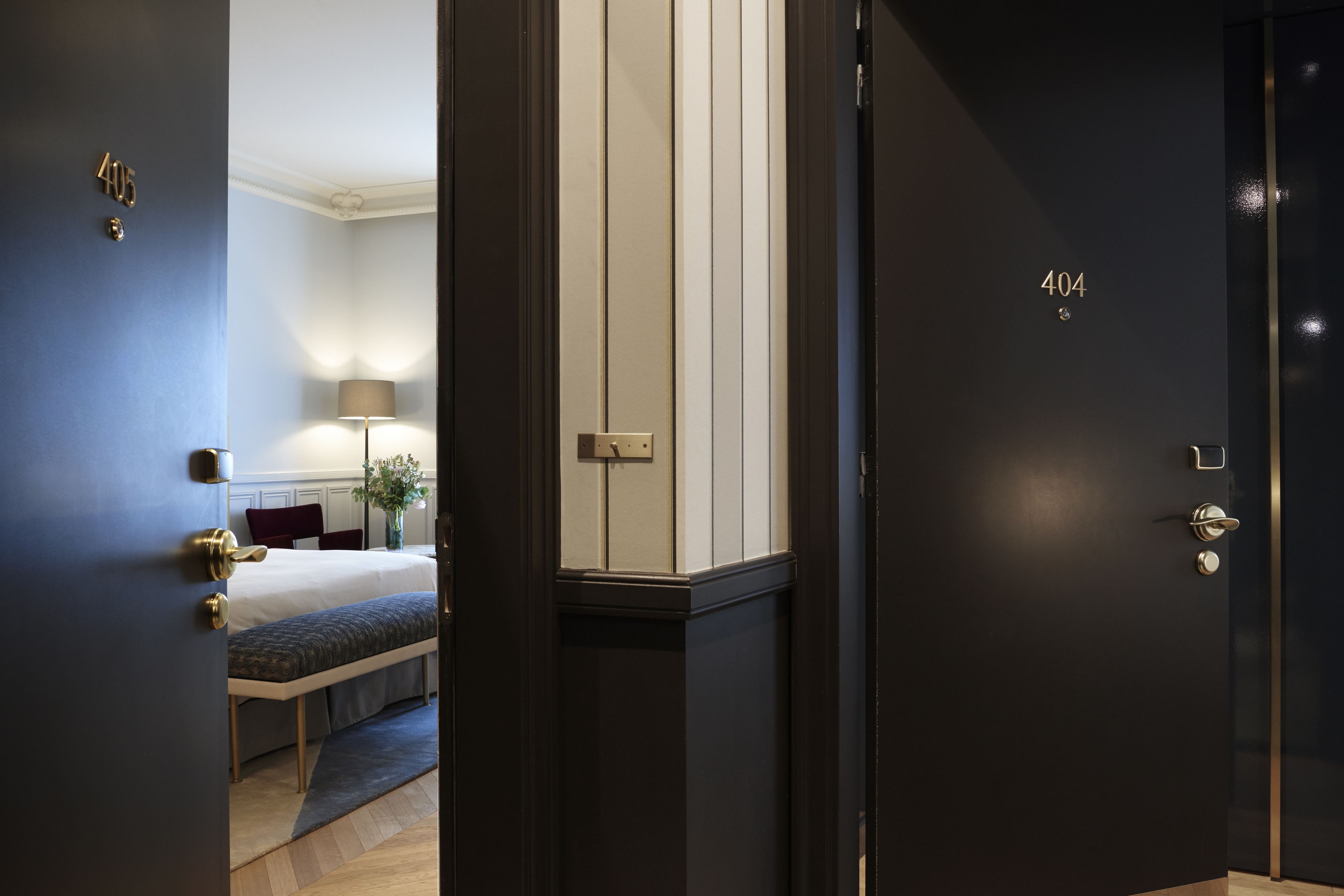 A hotel room with a bed, bedside table, lamp, and a door labeled "404".