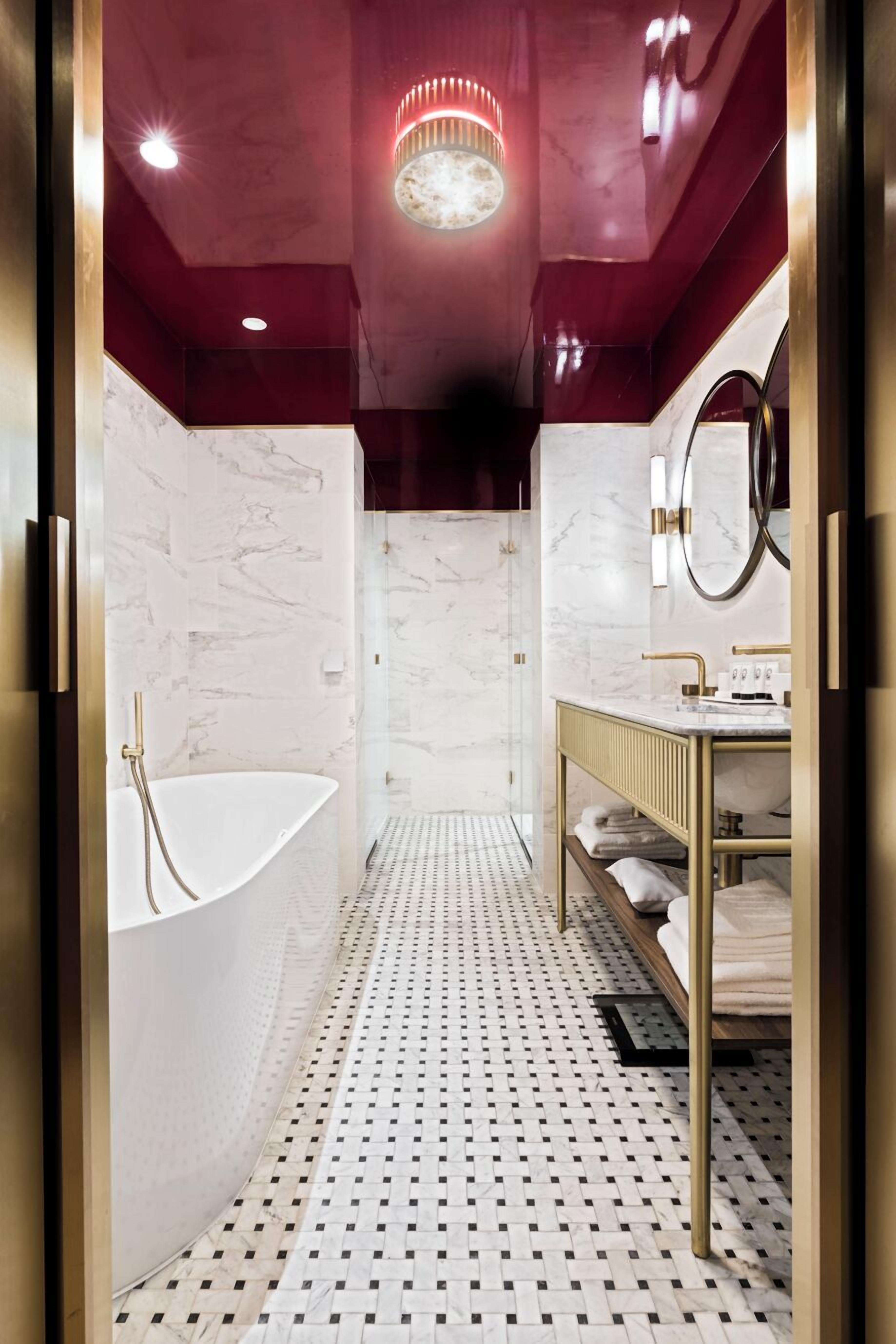A modern bathroom with a freestanding bathtub, a vanity with a mirror, and a patterned floor.