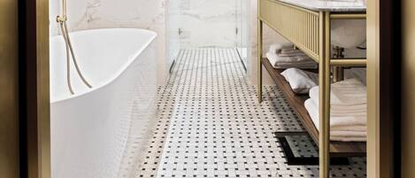 Un baño moderno con una bañera independiente, un tocador con espejo y un piso con diseño.