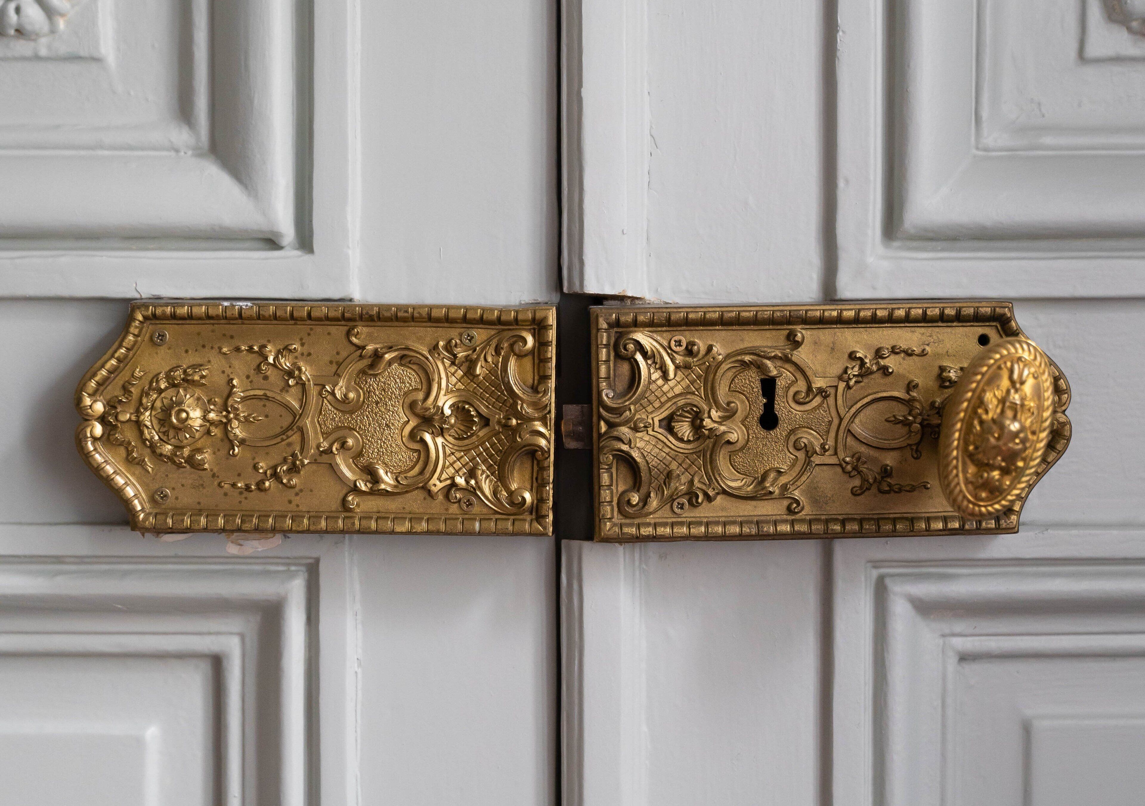 A white door with ornate, gold-colored door handles.