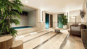 Un espace spa moderne comprenant une piscine, un coin salon avec un canapé et une grande plante en pot.