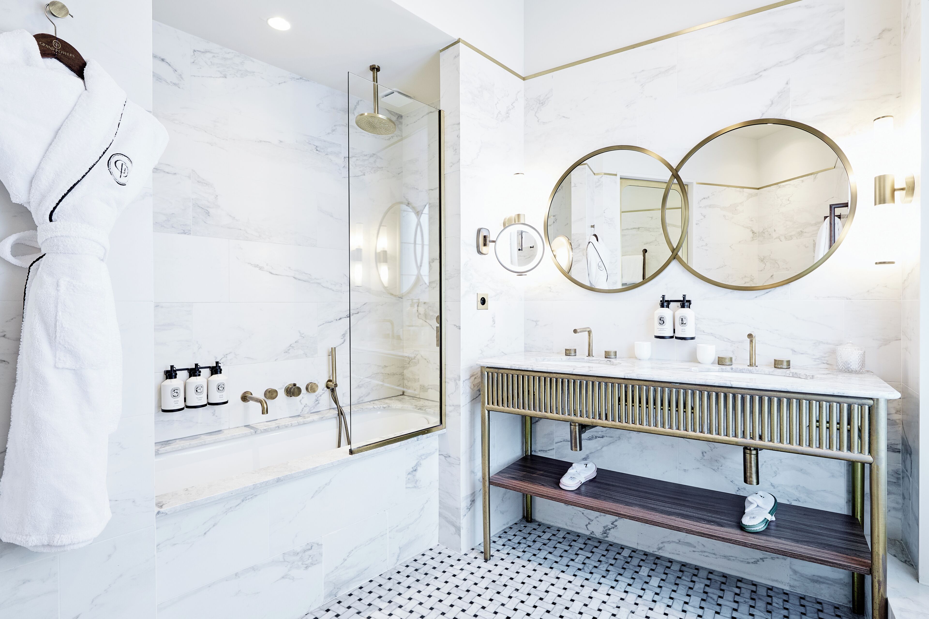 Une salle de bain moderne avec une douche en verre, un meuble-lavabo doté de deux miroirs et un peignoir accroché au mur.