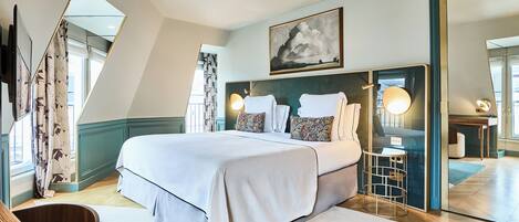 Una habitación de hotel moderna con una cama grande, un escritorio, una silla, un espejo y un cuadro en la pared.