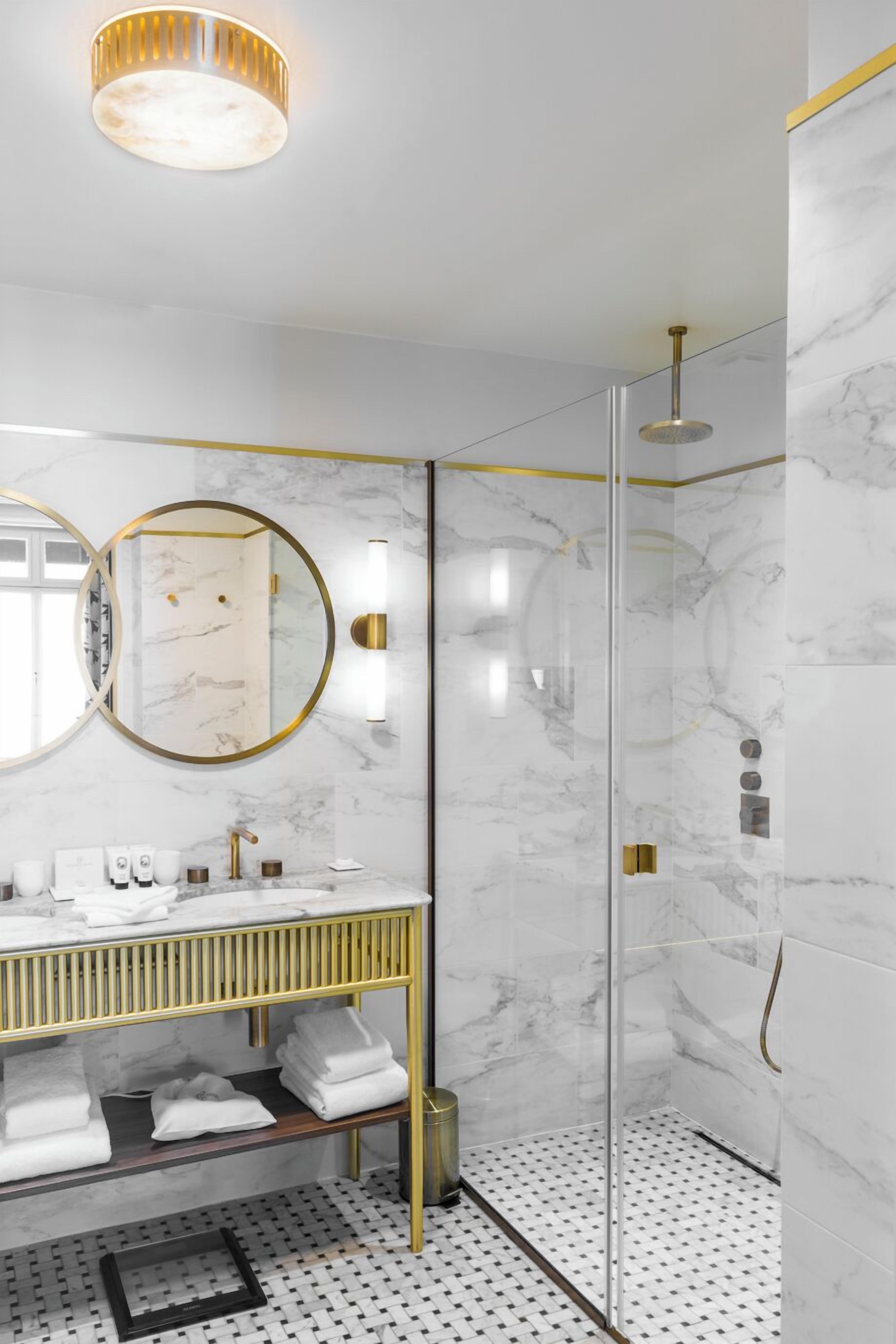 Un baño moderno con cabina de ducha de vidrio, tocador de mármol y un espejo grande.