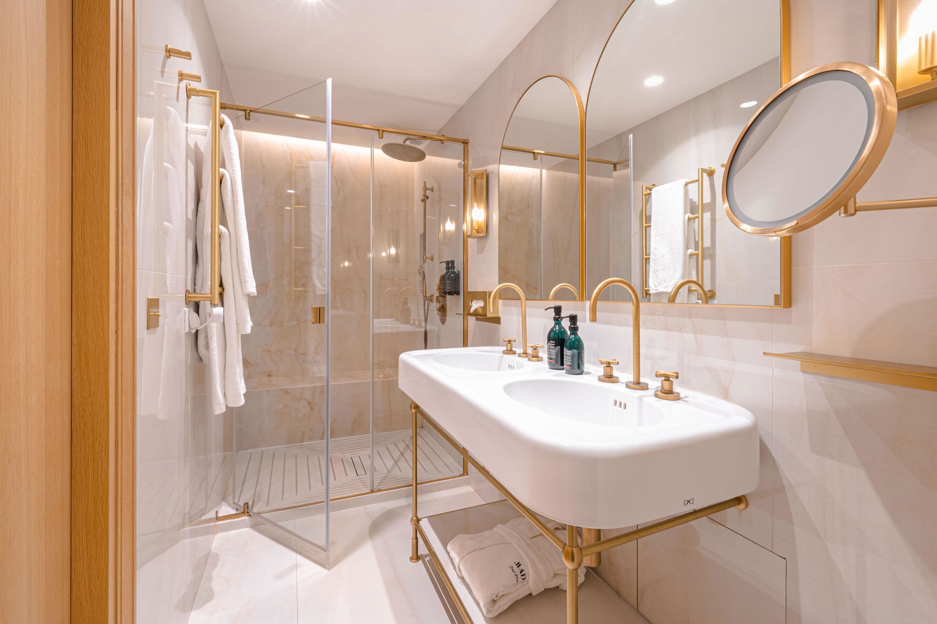 A modern bathroom with dual sinks, a glass shower enclosure, and a large mirror.