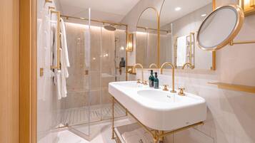 A modern bathroom with dual sinks, a glass shower enclosure, and a large mirror.