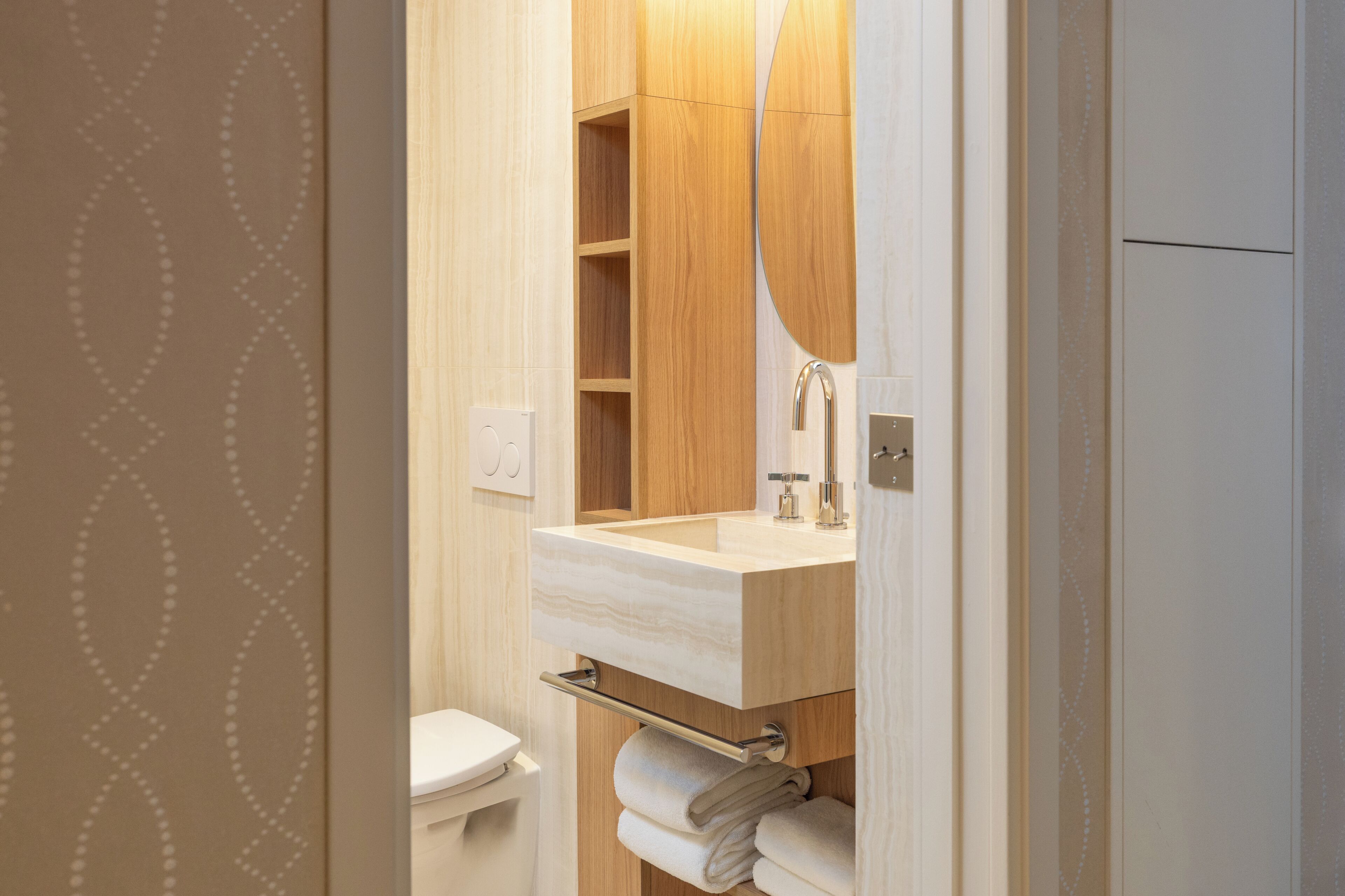 A modern bathroom with a wooden vanity, a mirror, and a towel rack.