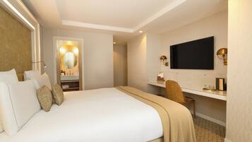 Una habitación de hotel con una cama grande, televisión, escritorio y espejo.