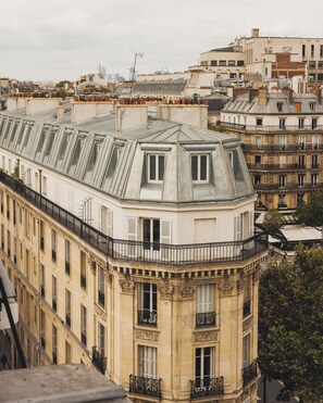 Un bâtiment historique doté d’un balcon d’angle remarquable, de grandes fenêtres et d’un toit plat agrémenté de lucarnes.