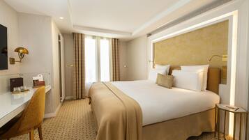 A hotel room with a large bed, a desk, a chair, and a television.
