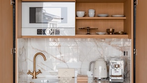 A kitchen with a Bosch refrigerator, a coffee machine, and a marble countertop. - Hôtel Madison (Paris)