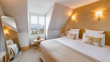 Una camera d'albergo con un letto grande, un comodino, uno specchio e una finestra con vista sulla città.