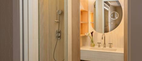 Un baño con ducha, lavabo con espejo y toallero.
