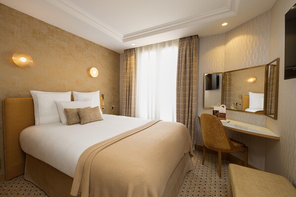 Una habitación de hotel con una cama grande, un escritorio, una silla y un espejo.