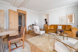 A modern living room with a wooden dining table, a sofa, and a coffee table. - Hôtel Madison (Paris)