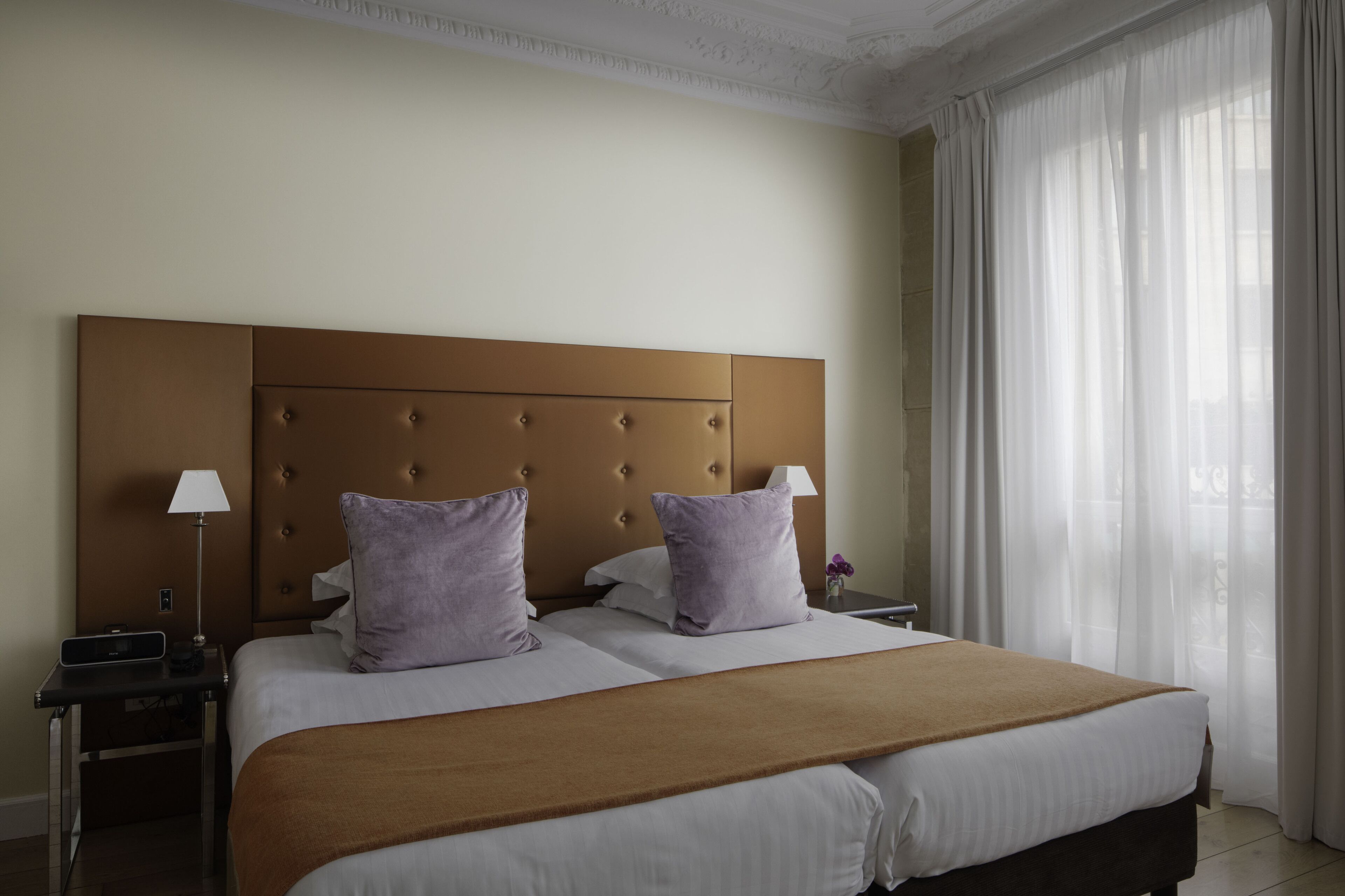 Habitación de hotel con una cama grande, dos mesitas de noche y una ventana con cortinas traslúcidas.