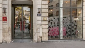 A hotel entrance with a glass door, numbered 123, and a display of model buildings outside. - Hôtel Le 123 Elysées - Astotel (Paris)