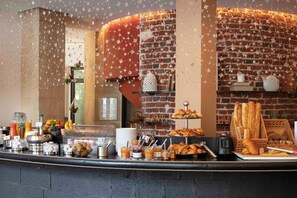 Un buffet de petit-déjeuner proposant une variété d’aliments et de boissons, un mur en briques et une vitrine.