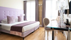 A hotel room with a large bed, a glass table, a chair, a lamp, and a mirror. - Hôtel Le 123 Elysées - Astotel (Paris)