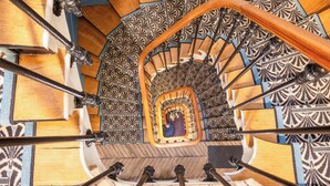 Un escalier en colimaçon orné de carreaux noirs et blancs formant un motif décoratif et doté d’une main courante en bois.