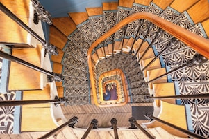 Un escalier en colimaçon orné de carreaux noirs et blancs formant un motif décoratif et doté d’une main courante en bois.
