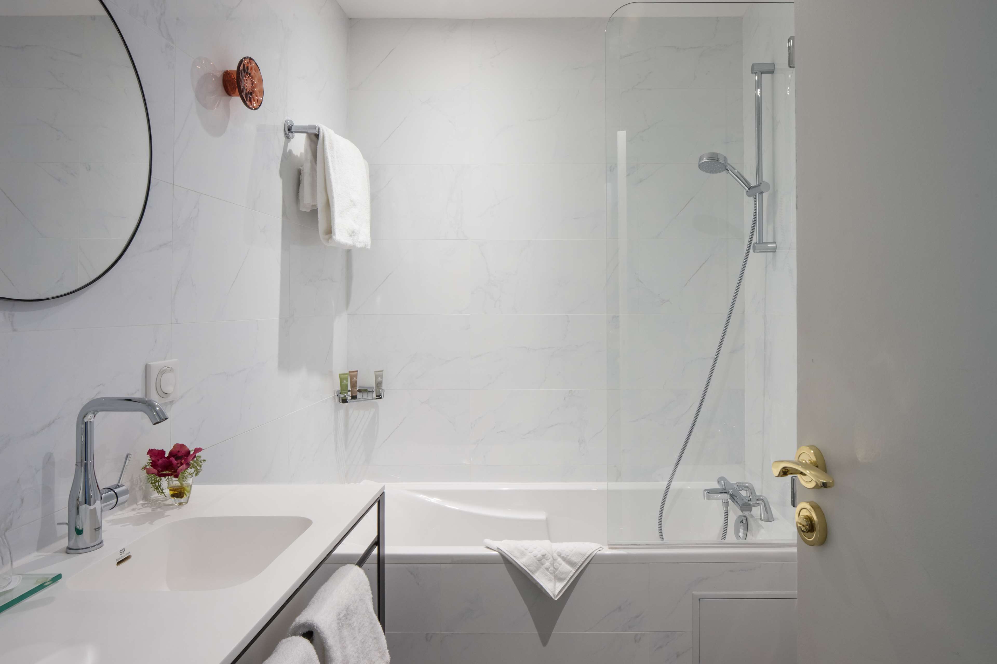 A modern bathroom with a bathtub, a shower, a sink, and a mirror.