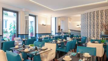 Un espace de restauration moderne, avec des chaises de couleur turquoise et des tables noires, et un aménagement intérieur épuré et élégant.