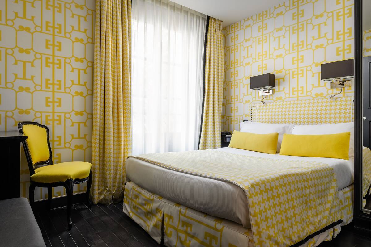 A hotel room with a bed, a chair, a desk, and a nightstand.