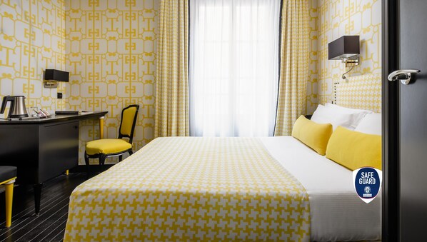 A hotel room with a bed, a desk, a chair, and a safe guard sign. - Hôtel Monceau Elysées (Paris)