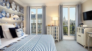 Quarto de hotel com uma cama grande, televisão, escrivaninha e vista para a cidade.